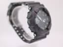 Angled left side view of the Casio G-Shock GA-110 on a watch stand, showing pushers and strap texture.