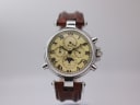 Front view of Stauer DS 13372 watch with cream dial, Roman numerals, moon phase, and brown leather strap on a stand.