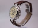 Angled side view of the Stauer watch, showing the polished silver case, crown, pushers, and brown leather strap.