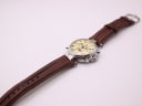 Top-down view of the Stauer watch laid flat, showing the full length of the brown leather strap and silver buckle.