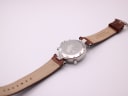 Back view of the Stauer watch laid flat, showing the case back engraving and the inside of the brown leather strap with 20mm lug width mark.