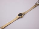 Top-down view of the gold tone Citizen watch laid flat, displaying the full length of the mesh bracelet and oval dial.