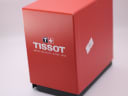 Side view of the red original Tissot outer watch box, showing branding and minor surface marks.