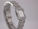 Angled side view of the Tissot L910 watch and its integrated steel bracelet on a display stand.