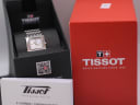 The Tissot L910 watch displayed in its original Tissot branded black inner box, with red outer box and original papers nearby.