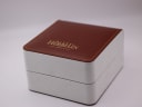 External view of the original Michel Herbelin branded presentation box with a brown leatherette top and white base.