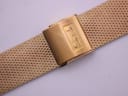 Close-up of the gold-tone mesh bracelet's fold-over clasp, showing 'Tissot' signature.