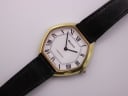 Angled close-up view of the gold octagonal Bulova Longchamp watch dial with white face and black Roman numerals on a black leather strap.