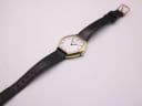 Three-quarter view of the Bulova Longchamp watch with the black leather strap extended, showcasing the gold octagonal case and white dial.
