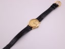 Overhead view of the entire Raymond Weil 9920 watch and black leather strap with gold buckle on a white surface.