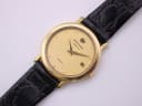 Close-up front view of the Raymond Weil 9920 textured gold dial with 'RW' logo, date window, and quartz text.