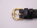Close-up of the gold-tone buckle of the Raymond Weil watch, featuring the 'RW' brand logo.