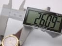 Digital caliper measuring the watch case diameter, with the display clearly showing '26.09 mm'.
