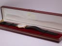 Side view of the Mappin & Webb watch nestled in its open original burgundy presentation box with gold accents.