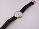 Overhead view of the Mappin & Webb watch lying flat, showing the full length of the black leather strap and gold-plated buckle.