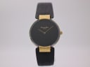 Front view of the Christian Dior Dark Moon watch on a display stand, showing black dial, gold case, and black leather strap.