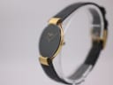 Side profile of the Christian Dior watch on a stand, highlighting the thin gold case and crown.