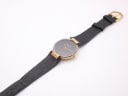 Top-down view of the Christian Dior watch with its full black leather strap on a white background.