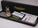 Michel Jordi watch displayed next to its original black presentation box and authenticity papers, including a guarantee card dated 8.12.98.