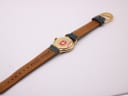 Rear view of the Michel Jordi watch and strap, showing the gold-tone case back with a Swiss emblem sticker, and the Michel Jordi embossed brown leather lining of the strap.