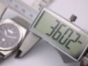 Digital caliper display showing a precise case size measurement of 36.02mm, with the watch blurred in the background.