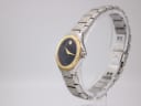 Side view of the Movado SE watch on a display stand, highlighting the two-tone case and bracelet design.