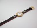 Top-down view of the Michel Jordi watch with its distinctive black leather strap featuring white daisy embroidery.
