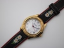 Close-up of the Michel Jordi watch dial and gold-tone bezel with embossed animal figures.
