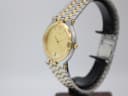 Side profile view of the Gucci 9000 M watch on a display stand, showing the signed gold crown and two-tone case.