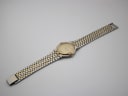 Full length top-down view of the Gucci 9000 M two-tone watch and integrated bracelet against a white background.