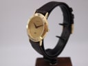 Side profile view of the Gucci 3000 M watch on a display stand, showing the slim gold case and brown leather strap.