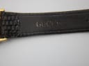 Close-up of the inside of the brown leather strap, showing the embossed "GUCCI" lettering and lizard-like texture.