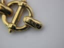 Macro shot of the gold-tone fold-over clasp from the Gucci 6400 L bracelet, engraved with the 'GUCCI' logo.