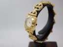 Angled right-side view of the gold-tone Gucci 6400 L watch on a display stand, highlighting the crown and integrated bracelet.