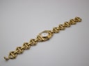 Overhead view of the Gucci 6400 L watch with its integrated gold-tone bracelet fully extended against a white background.