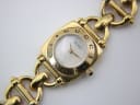 Close-up of the Gucci 6400 L dial and bezel, showing the 'GUCCI' text, white mother of pearl dial, and gold-tone hands.