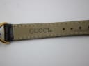 Close-up of the inside of the black leather strap, showing the embossed 'GUCCI' and 'GENUINE LEATHER' markings.
