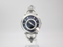 Front view of the Gucci 122.5 watch with a deep blue dial and steel horse-bit bracelet, displayed on a stand.