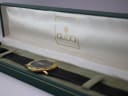 The Gucci 3000.2.M watch nestled inside its open original dark green Gucci presentation box, with 'GUCCI' logo on the satin lining.