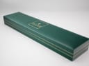 The original dark green Gucci presentation box, closed, showing the gold line detailing and 'GUCCI' logo on the lid.