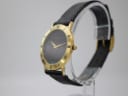 Angled side view of the Gucci 3000.2.M watch on a display stand, highlighting the gold tone case and roman numeral bezel.