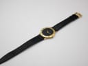 Overhead view of the Gucci watch laid flat, displaying the full length of the black leather strap.
