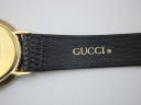 Close-up of the black leather strap's underside, with 'GUCCI' branding embossed in gold.