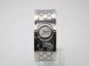 Front view of the Gucci 112 Twirl watch, showcasing its mother-of-pearl dial and engraved stainless steel bangle on a display stand.