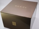 Exterior view of the Gucci branded brown box, showing the gold Gucci logo and a label indicating 'MARINA W/MOP 3D/SS'.