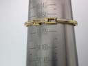 Close-up of the integrated gold-tone bangle bracelet on a wrist sizing gauge, showing a wrist circumference of 155mm / 15.5cm, with a signed 'GUCCI' clasp.