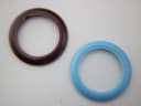 Close-up top-down view of two interchangeable bezels, one dark brown and one light blue, against a white background.