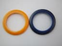 Close-up top-down view of two interchangeable bezels, one orange and one dark blue, against a white background.