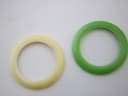 Close-up top-down view of two interchangeable bezels, one cream and one bright green, against a white background.
