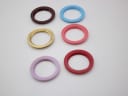 Top-down view of another six assorted coloured and gold-tone interchangeable bezels laid out on a white surface.
